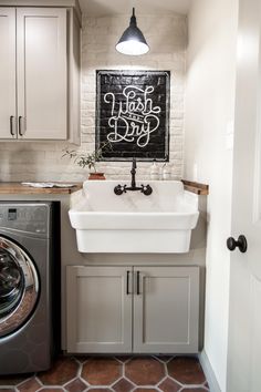 a washer and dryer in a room with white walls, brown flooring and cabinets