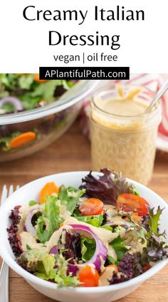 a white bowl filled with salad and dressing next to a glass of dressing on a wooden table