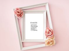 a white frame with pink flowers and a quote in it on a pink wall background