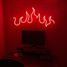 a red neon sign in the corner of a room with a computer desk and chair