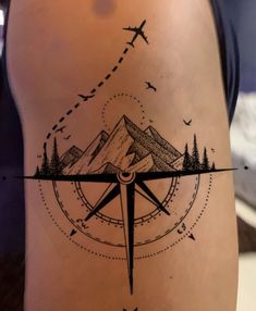 a person with a compass tattoo on their leg and an airplane flying over the mountain