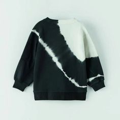 a black and white tie dye sweatshirt hanging on a wall