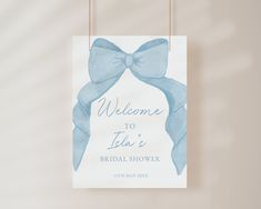 a welcome sign with a blue bow hanging from it's side on a wall