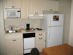 a small kitchen with white cabinets and black stove top oven next to a refrigerator freezer