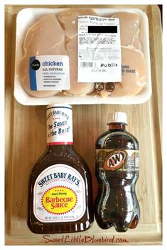 two bottles of hot sauce and some meat in a tray