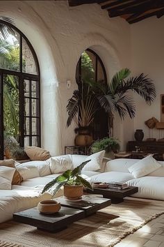 a living room filled with lots of white furniture and large arched windows above the couches