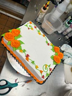 there is a cake that has been decorated with orange flowers and green leaves on it