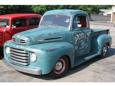 two old trucks parked next to each other in a parking lot