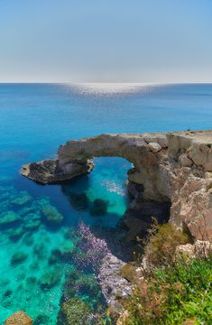 the water is crystal blue and clear, with an arch in the middle that extends into the ocean