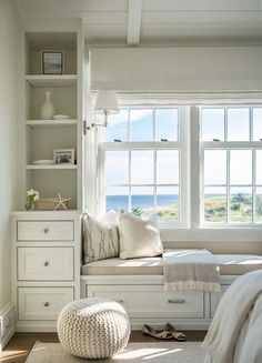 a bedroom with white furniture and windows overlooking the ocean