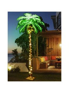 a palm tree with lights on it in front of a deck and patio at night