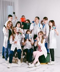 a group of people standing and sitting around each other in front of a white wall