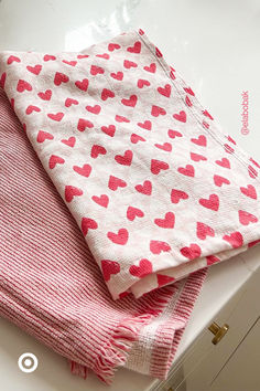 two towels folded on top of each other with hearts printed on them, sitting on a counter