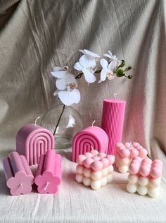 some pink and white items sitting on a table next to a vase with flowers in it