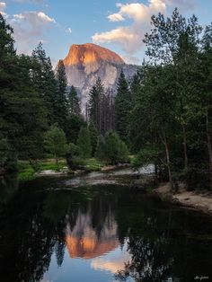 a mountain is reflected in the still water of a river with trees and rocks around it