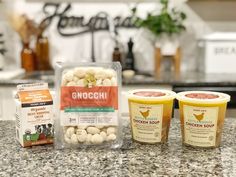 three ice creams sitting on top of a counter next to two cups filled with food