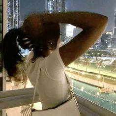 a woman standing on top of a balcony next to a tall building