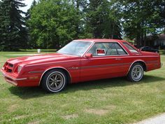 a red car parked on top of a lush green field