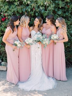 the bride and her bridesmaids pose for a photo in front of some greenery