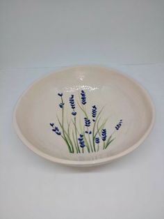 a white bowl with blue flowers painted on the side and green stems growing out of it