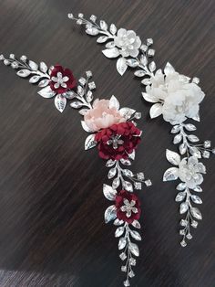 three flower brooches on a table with one being red and the other is white