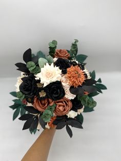 the bridal bouquet is made up of black, white and orange flowers with green leaves