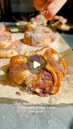 a person sprinkling sugar on pastries that are sitting on wax paper with the words okay, these are my cinnamon others