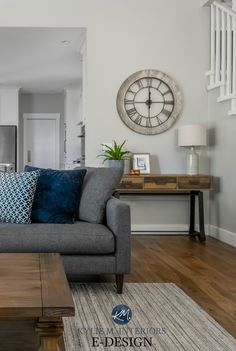 a living room with a couch, coffee table and clock on the wall above it