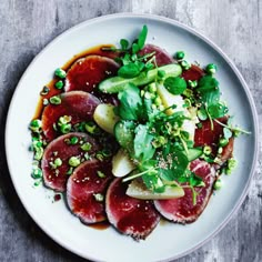 a white plate topped with meat and veggies on top of a wooden table