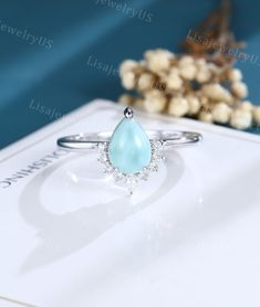 a white gold ring with a pear shaped aqua blue topazte surrounded by diamonds