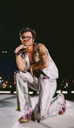 a man sitting on the ground wearing striped pants