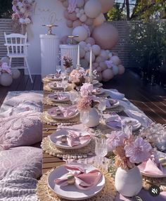 the table is set with pink and white plates, napkins, and vases