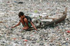 a young boy sitting on the ground next to a boat