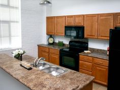 an empty kitchen with granite counter tops and black appliances in the corner, next to a window