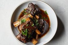 a white plate topped with meat covered in gravy and garnished with parsley