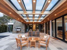 an outdoor patio with wooden furniture and glass ceiling