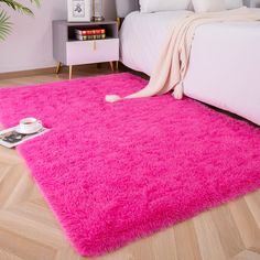 a bright pink rug is on the floor next to a bed