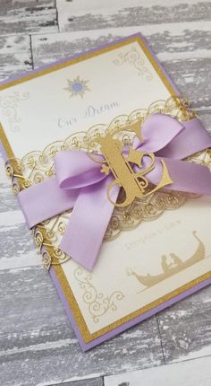 a purple and gold card with a bow on it