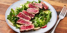 a white plate topped with meat and veggies on top of a wooden table