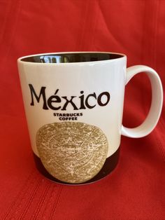 a starbucks coffee mug sitting on top of a red tablecloth covered table cloth with the word mexico written across it