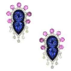 These exquisite stud earrings are a testament to unparalleled craftsmanship and timeless elegance. Featuring a total of 2.8 carats of vibrant blue sapphires, the design showcases 1.4 carats of two oval-shaped sapphires and 1.4 carats of two pear-shaped sapphires, artfully arranged side by side. Encircling these central stones are two radiant halos: the inner halo comprises 56 round blue sapphires totaling 0.46 carats, while the outer halo boasts 68 sparkling white round diamonds totaling 0.47 carats. Crown-like accents with 14 round pink sapphires totaling 1.48 carats add a regal touch, set in a secure 3-prong setting. Below, 10 drilled white round diamonds totaling 0.58 carats dangle gracefully. Crafted in luxurious 18k white gold and weighing a substantial 7.95 grams, these unique earrin Radiant Halo, Amazon River, Earring Stand, Vibrant Blue, Diamond Design, Ear Jewelry, Showcase Design, Side By Side, Unique Earrings