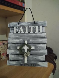 a wooden sign that says faith with a cross and wreath hanging from the side of it