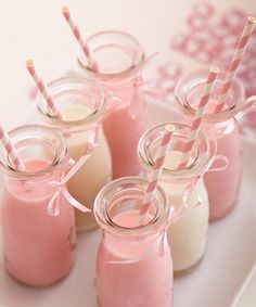 four mason jars filled with pink liquid and straws on a white plate next to two cups