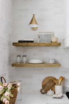 the shelves in this kitchen are made of wood and have white tiles on them, along with wooden utensils