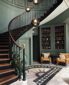 a spiral staircase in the middle of a room with two chairs and a bookcase