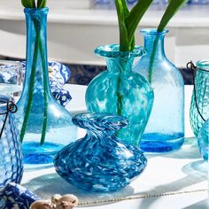 blue glass vases with flowers in them on a table