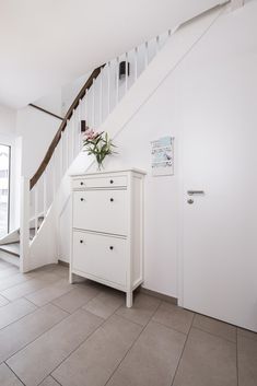 a white dresser sitting under a stair case