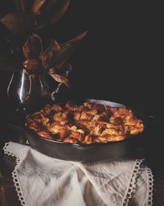 a pan filled with food sitting on top of a table next to a potted plant