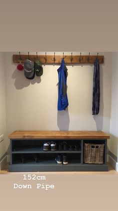 a coat rack with two coats hanging on the hooks and shoes below it, next to an entryway bench