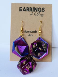 two purple and black dice earrings with gold earwires sitting next to each other